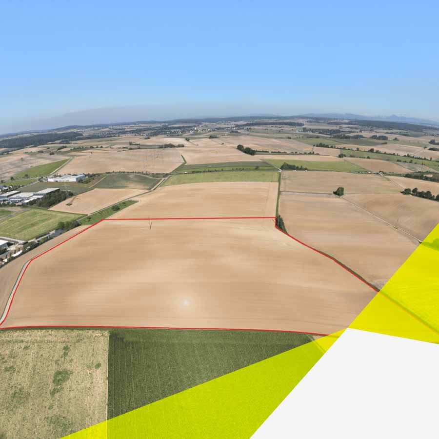 Es ist eine nicht sehr hohe Vogelperspektive. Am oberen Horizont ist Himmel zu erkennen. Neben vielen Feldern, ist im unteren Drittel ein ganz großes Feld, welches mit einer roten Linie markiert wurde. Die Linie kennzeichnet den zukünftigen Solarpark Zimmerbeg.