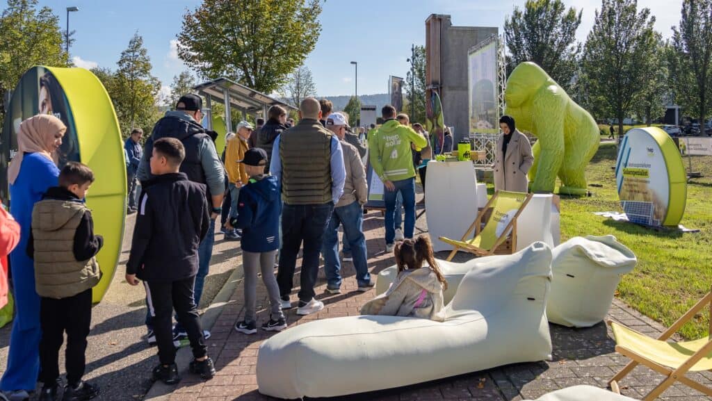 Personen stehen zwischen unterschiedlichen hellgrünen gebrandeten Elementen.