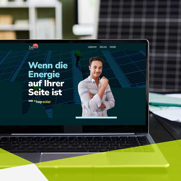 Ein aufgeklapptes Laptop auf einen Tisch stehend. Im Hintergrund ist ein volles Büro mit ein Solar Panel zu erkennen. Auf dem Bildschirm ist eine Webseite zu sehen, links oben steht Zaber Solar. Es ist eine große Überschrift zu lesen: Wenn die Energie auf Ihrer Seite ist.