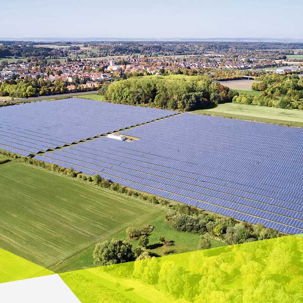 Ein Solarpark aus der Vogelperspektive. Hinten am Horizont siehr man noch eine kleine Stadt.