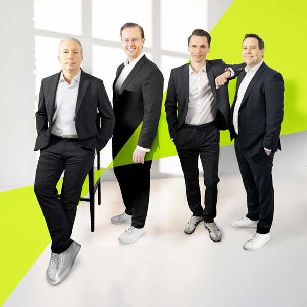 4 Personen stehen in einem sehr hellen, komplett weißen Raum und schauen direkt in die Kamera. Es ist das hep Global GmbH Management von links angefangen Christian Hamann, Georg von Eichendorff Strachwitz, Thomas Tschirf und Martin Vogt.