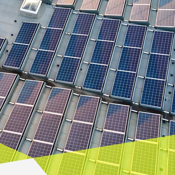 Vogelperspektive, ein großes weißes Industriedach mit einer Menge Solarmodulen.